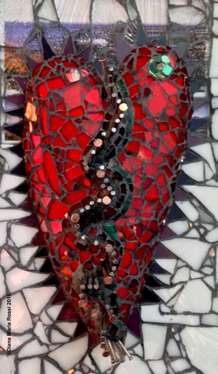 photo of glass mosaic heart/ the heart is read with copper and steel nails bisecting in a zigzag fashion. this is a detail image of the heart. also, there is a small green circle in the upper right hand section of the heart. the heart is really reddish orange