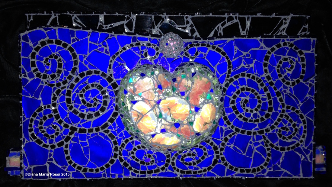 photo of glass heart/ the heart is made of transparent glass over photos of  orange/yellow roses that shine through/ there are flecks of cobalt and intense green interspersed throughout the heart. the background is cobalt blue with swirls of black and there is a pinkish orb above the heart