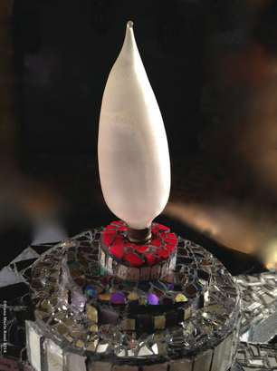 Picture of glass mosaic on wood detail with light bulb from the top and red glass glint of purple