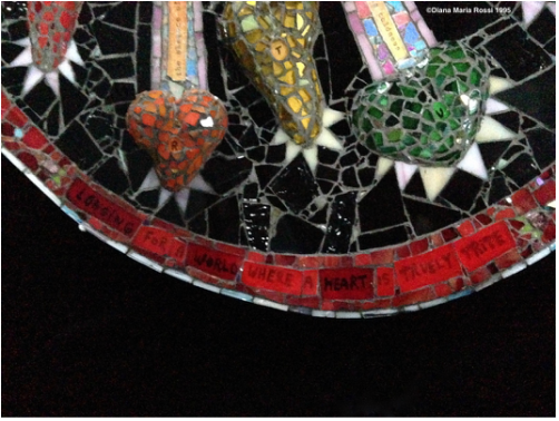 photo of glass mosaic detail, bottom part  with red, orange, yellow, green heart and text under red glass that reads: longing for a world where a heart is truely trite