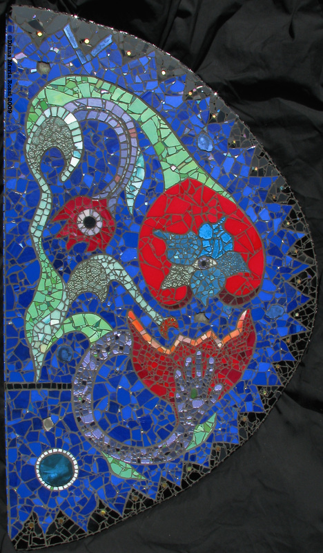Picture of art glass mosaic on cement board floral design with eyes and hand in greens, reds, purples on cobalt blue background with photographs