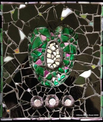 glass mosaic heart. The heard is green with purple specks on a black background with a silver oval in the center 