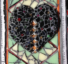 photo of glass mosaic heart and this is a detail of the heart which is black with white lacing down the middle, studded with multi-colored beads